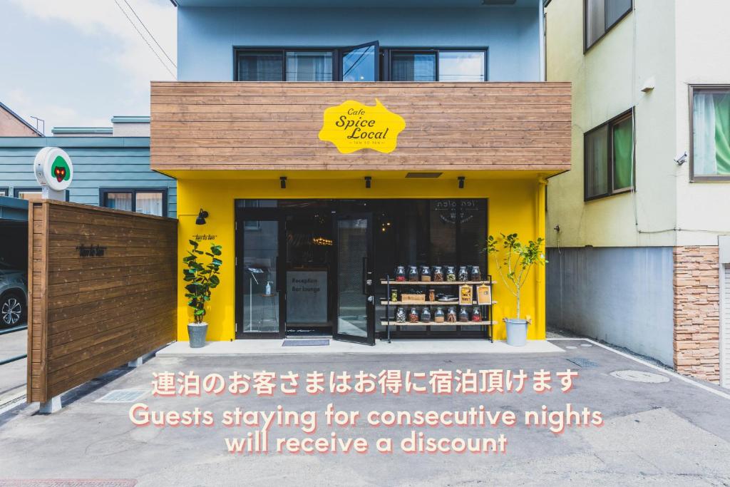札幌Ten to Ten Hostel的建筑前方有黄色标志的商店