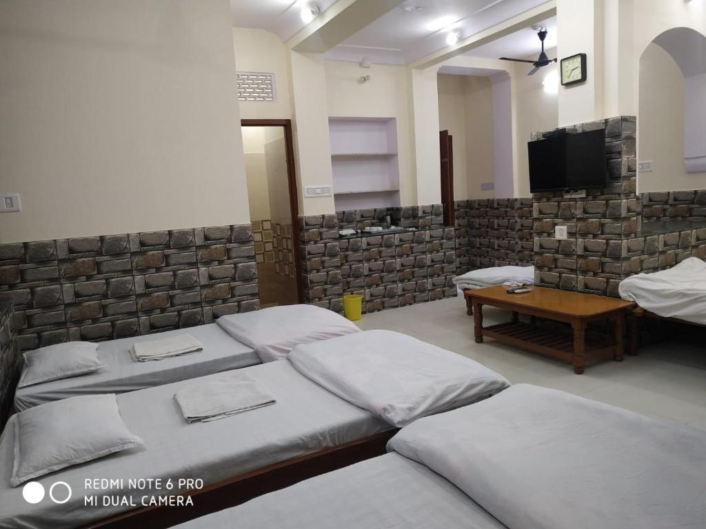 斋浦尔BOBY HOME STAY "BOBY MANSION" Jaipur的一间带四张床、一张桌子和电视的房间