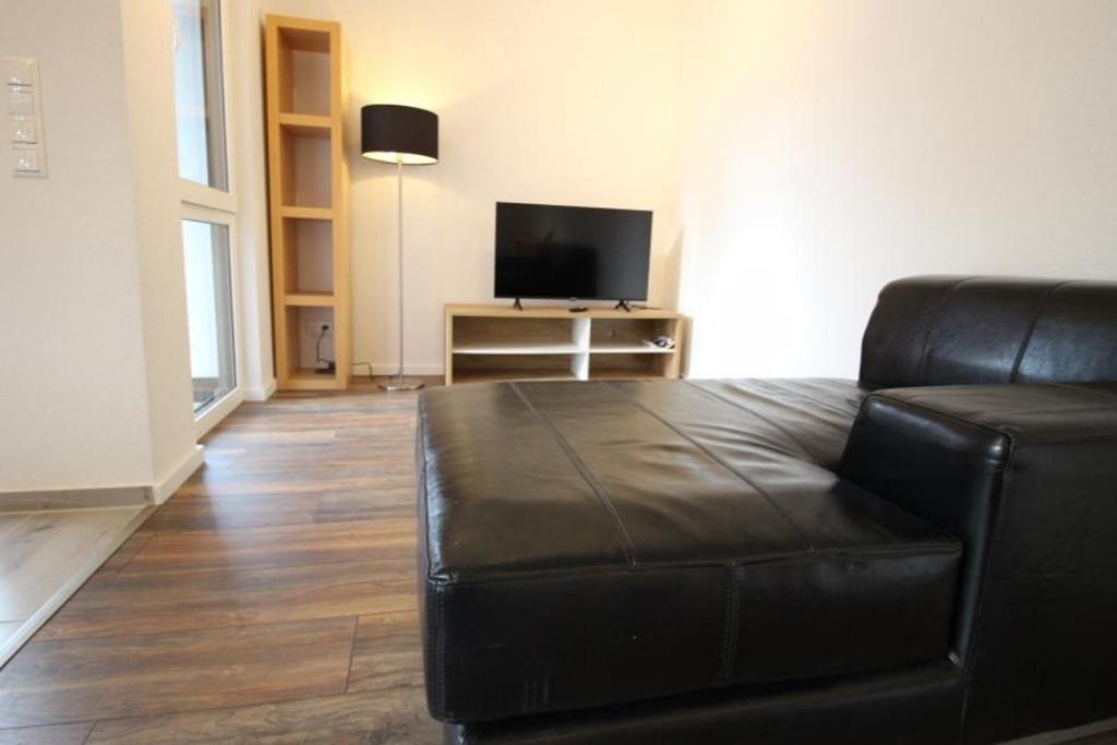 NEU! FeWo Marburg 2 mit Balkon的客厅配有黑色真皮沙发和电视