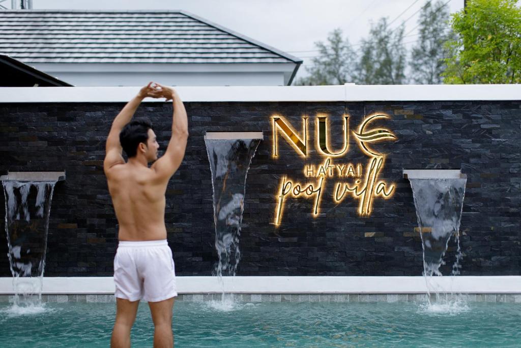 宋卡Nue Hatyai Pool Villa 147的站在喷泉前的水面上的人