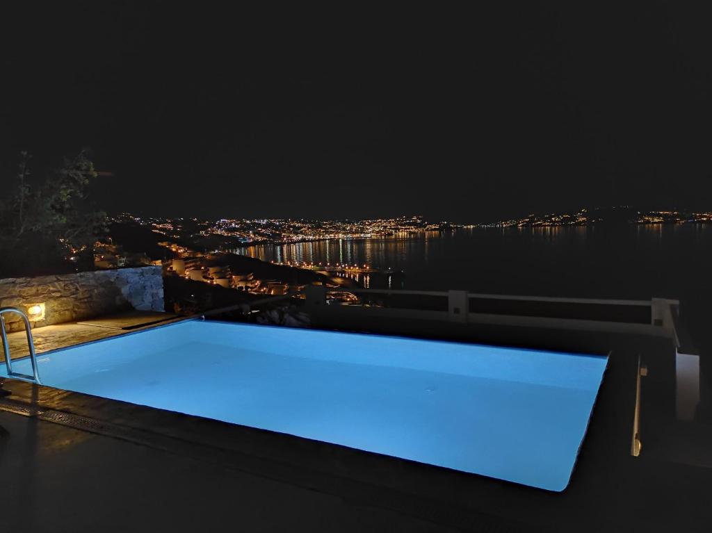 圣斯特凡诺斯Mykonian Luxury Villa Azure w Sea View and Pool的屋顶上的一个游泳池晚上点燃