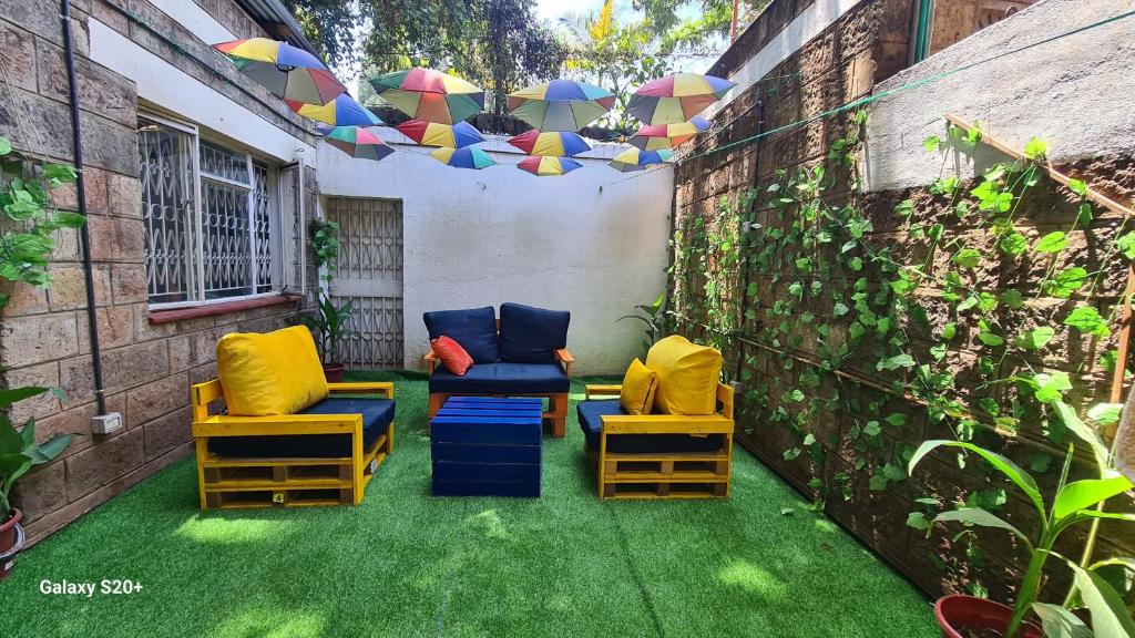 内罗毕Jabulani Nairobi Backpackers Hostel的草地上带椅子和遮阳伞的庭院