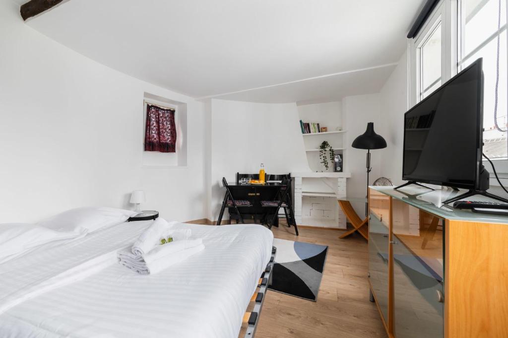 巴黎Agréable studio cœur de paris - Paris 6 - 2P的一间卧室配有一张床和一张书桌及电视