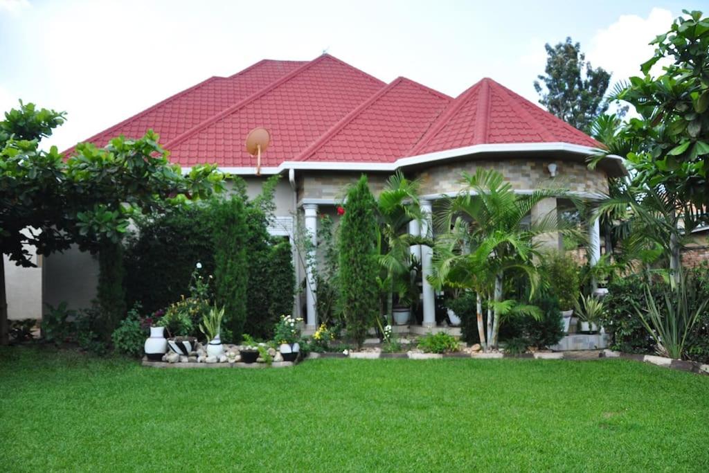 基加利VILLA MODERNE CHEZ YVONNE的一座红色屋顶的房子和一个院子