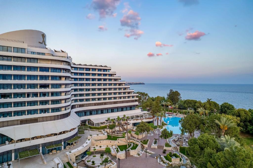 安塔利亚Rixos Downtown Antalya - The Land Of Legends Access的一座大建筑,在海洋前设有一个游泳池