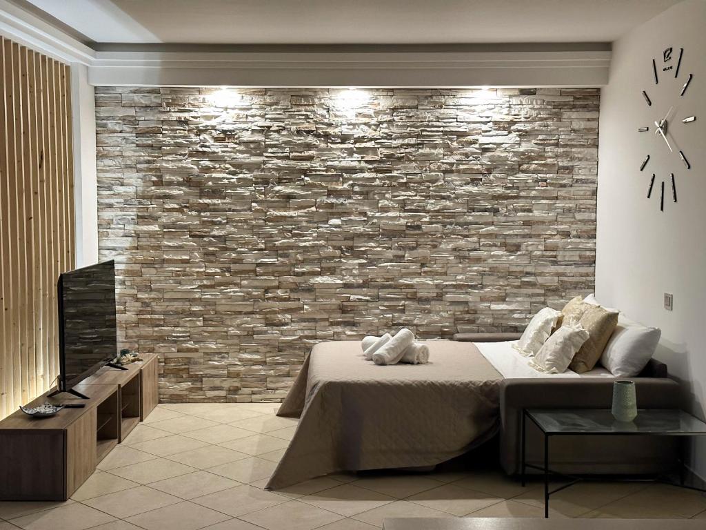 安格里Kiro Apartment Experience Pompei的卧室设有砖墙、一张床和一个钟
