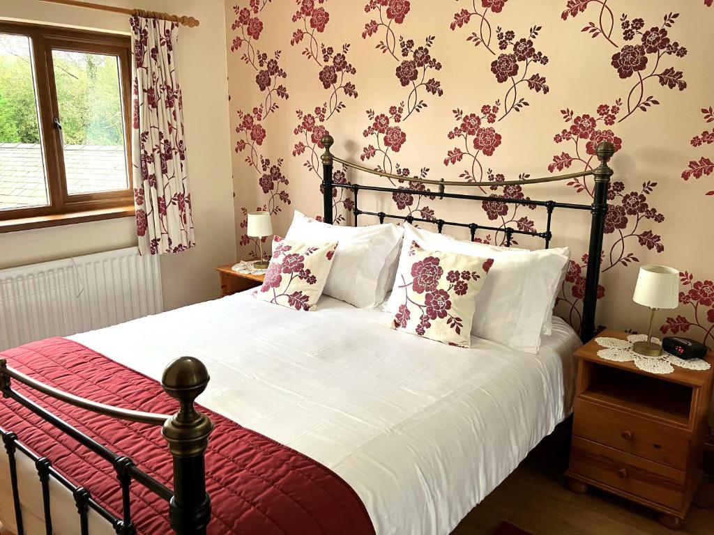 UldaleEmerald Bank Cottage的卧室配有一张墙上鲜花的大床