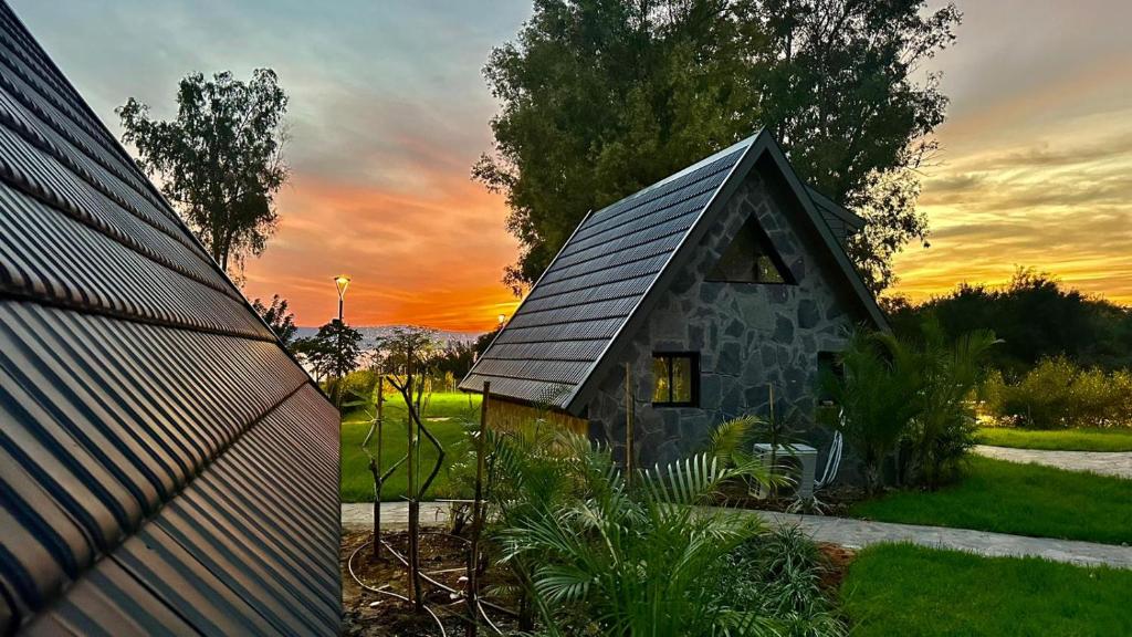 KinarDoga Resort - דוגה ריזורט的一座小石头房子,背景是日落