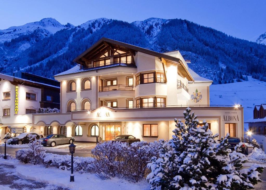 伊施格尔Hotel Albona的一座大雪楼,背景是群山