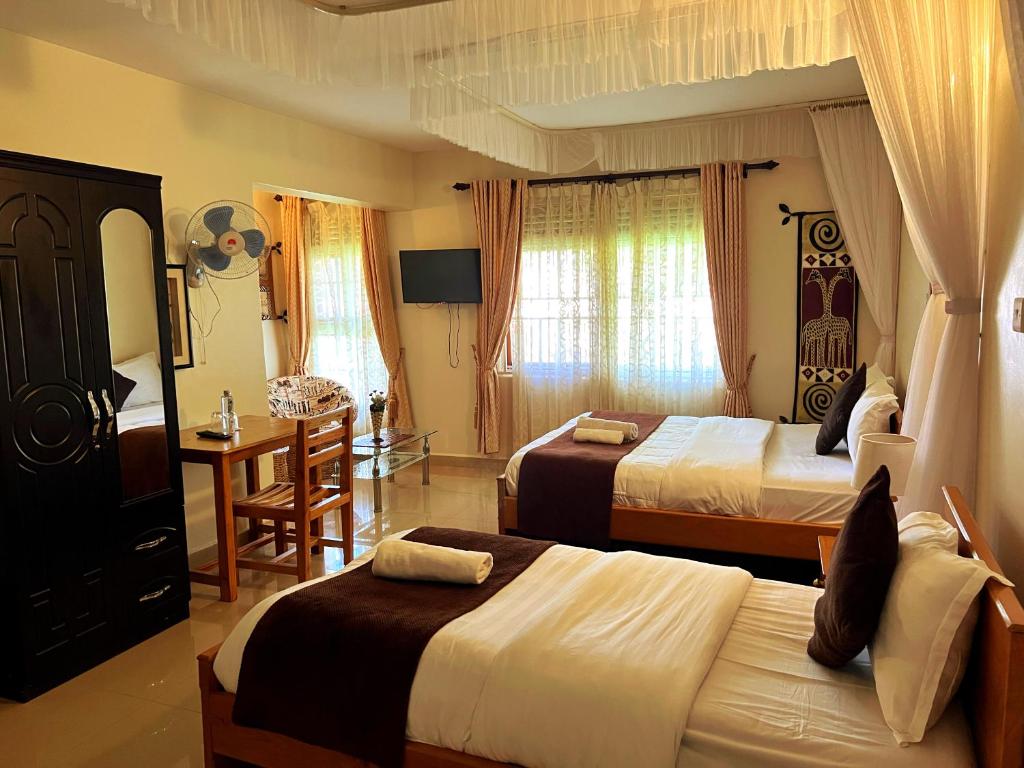 恩德培Sunset Hotel Entebbe的酒店客房设有两张床、一张桌子和一张书桌。
