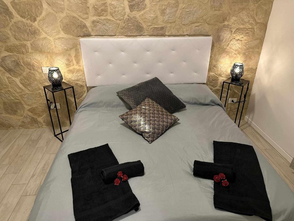 维罗纳Langolo di laura borgo roma destiny home 3的一张带黑色枕头和红色鲜花的床
