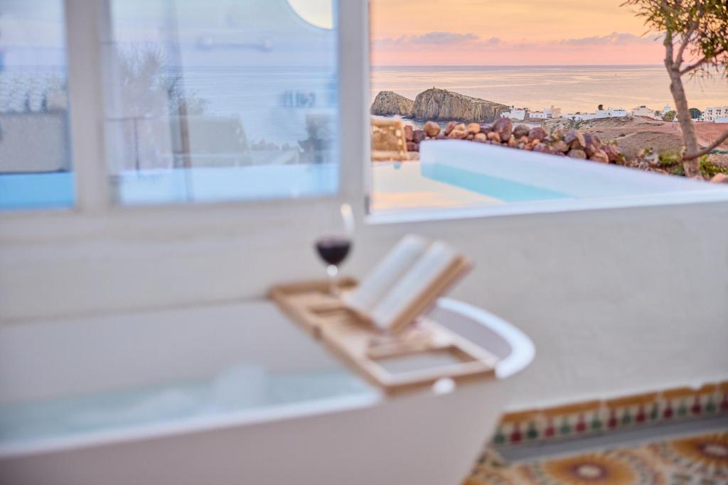 拉伊斯莱塔德尔摩洛Cortijo La Loma的靠窗边的沙滩椅,边喝一杯葡萄酒