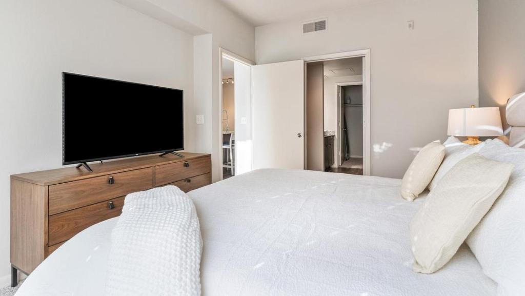 奥斯汀Landing - Modern Apartment with Amazing Amenities (ID7779X23)的白色卧室设有一张大床和电视。