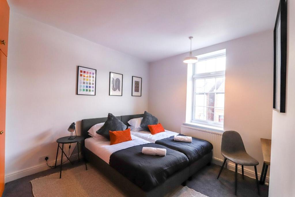 LongleyBeautiful 3 Bedroom House - Sleeps 5 Free Parking的一间卧室配有黑色皮革床和橙色枕头