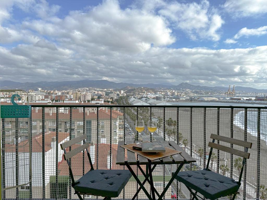 马拉加Apartamento Mirador del Mediterráneo的阳台上的桌子和两杯葡萄酒