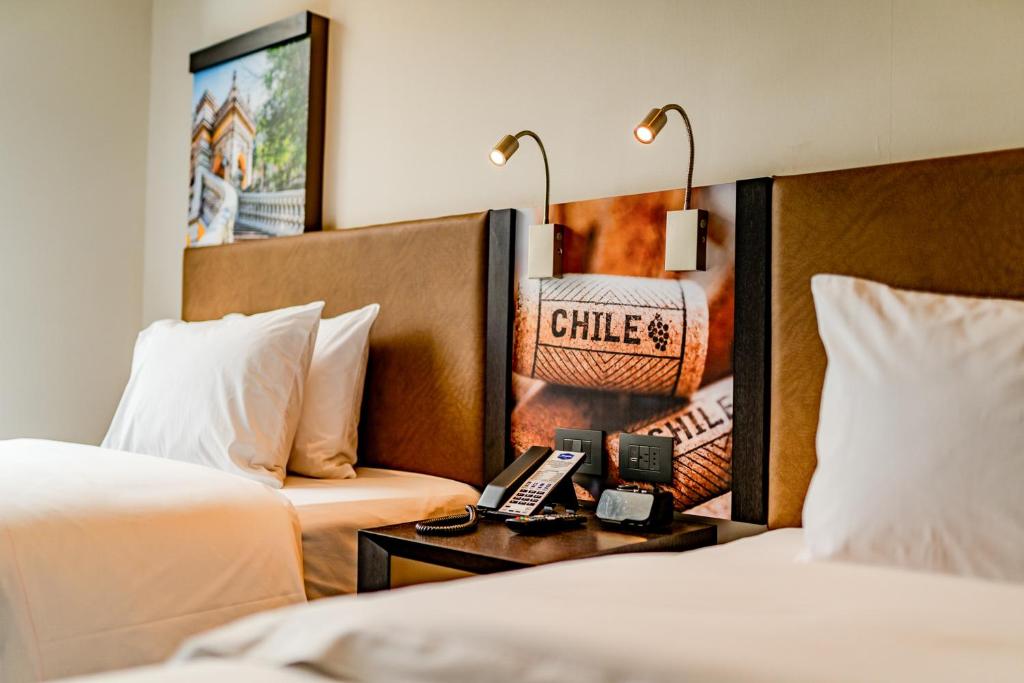 圣地亚哥Hampton By Hilton Santiago Las Condes的酒店客房设有两张床和一张桌子及电话