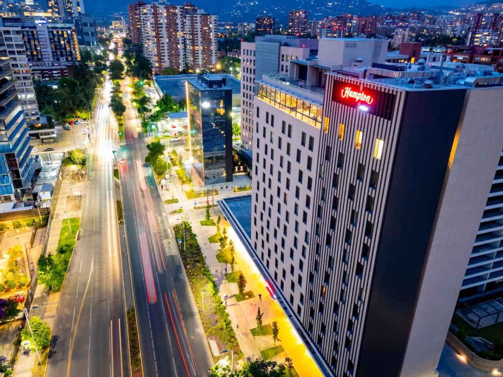 圣地亚哥Hampton By Hilton Santiago Las Condes的城市天际线,夜晚有高大的白色建筑