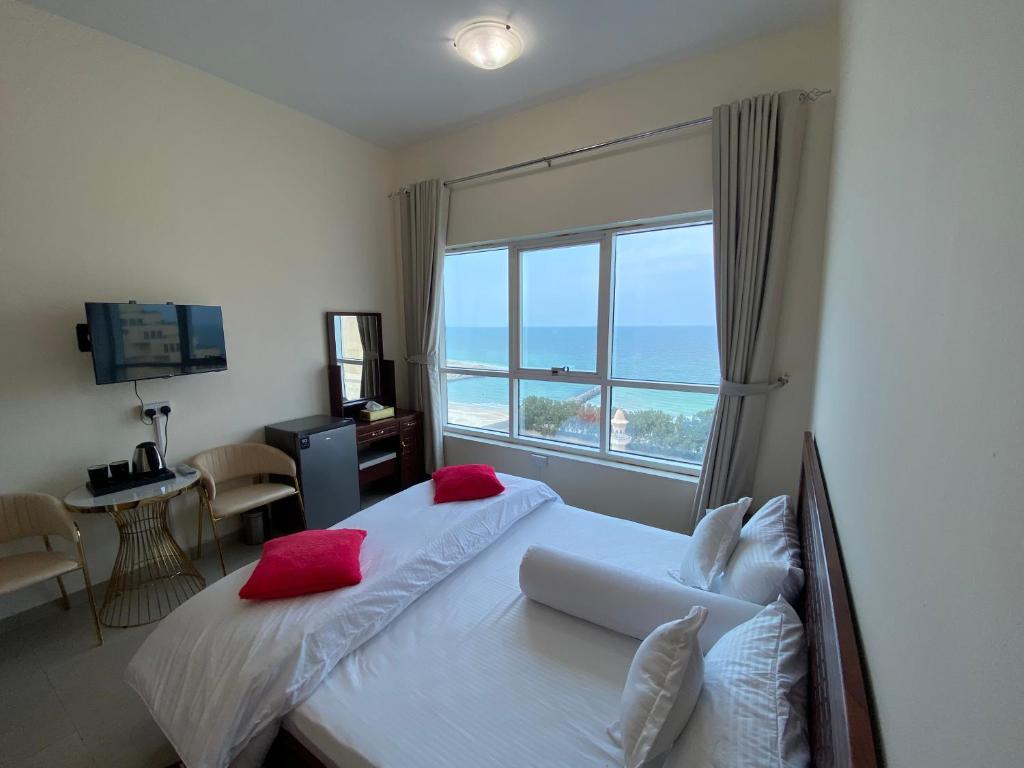 阿吉曼Family rooms with beach view的一间卧室配有一张带红色枕头的床和一扇窗户