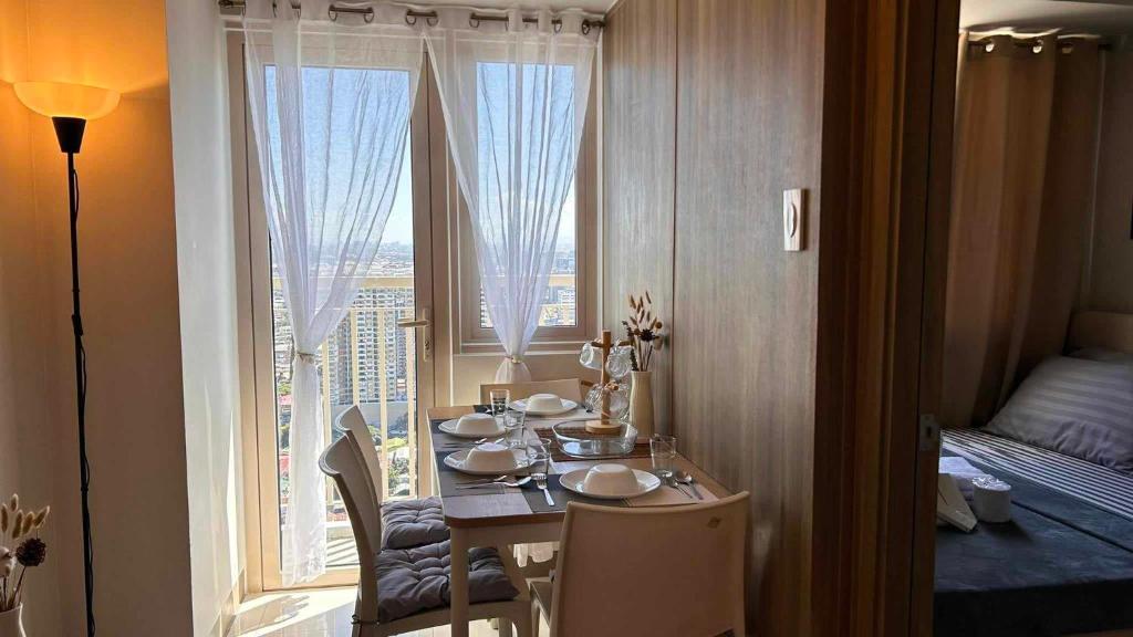 马尼拉Smdc Breeze Residences的客房设有桌子和大窗户。