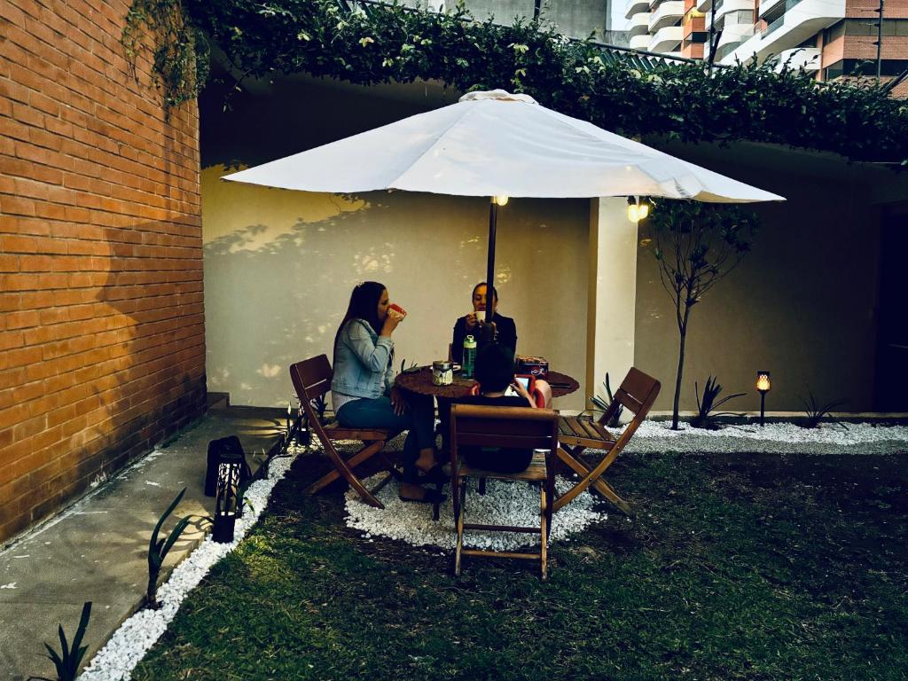 危地马拉NoMAD House的两个人坐在桌子下,伞下