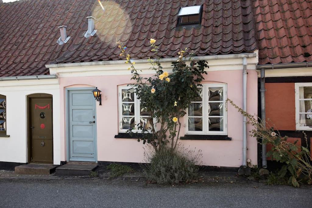 马斯塔尔Skønt fiskerhus. Tæt på by, havn og havet的粉红色和白色的房子,有蓝色的门