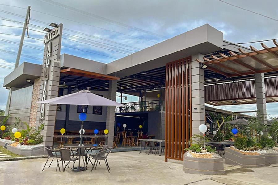 QuezonAgathas Hotel powered by Cocotel的一座配有桌椅和雨伞的建筑