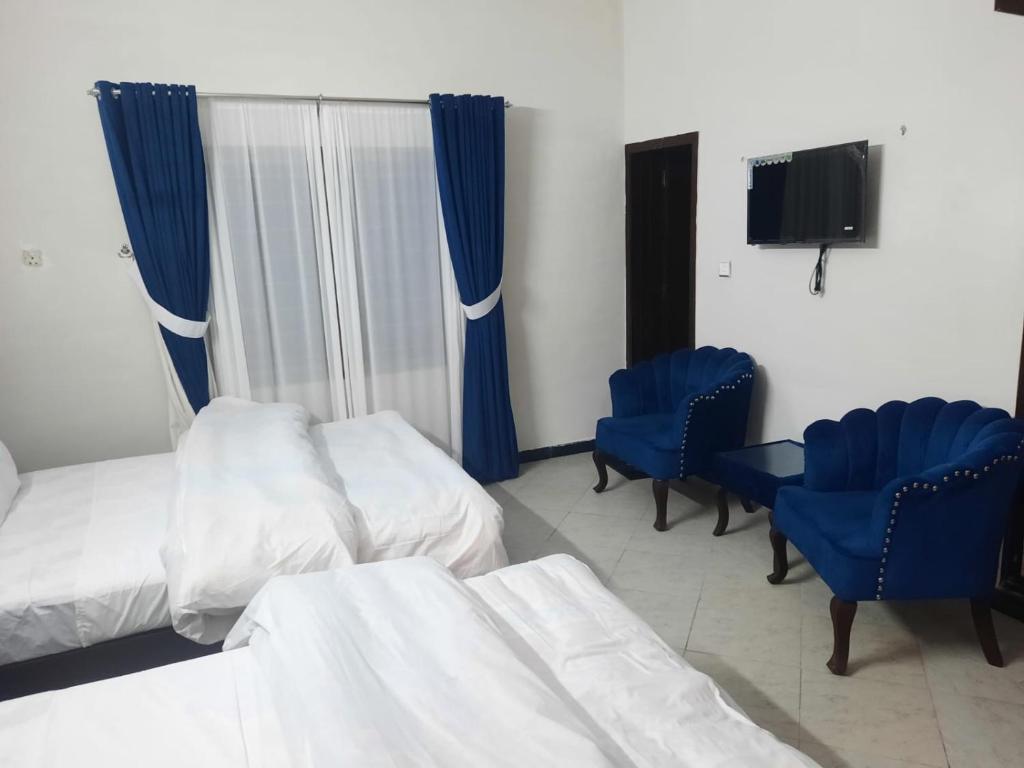伊斯兰堡Morbex Guest House Islamabad的酒店客房,配有两张床和蓝色椅子