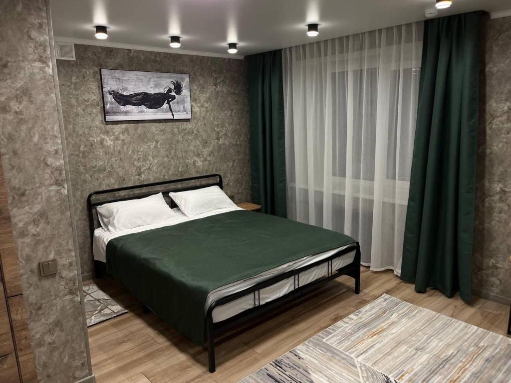 彼得罗巴甫洛夫斯克DEMAL HOTEL的一间卧室配有一张带绿色棉被的床