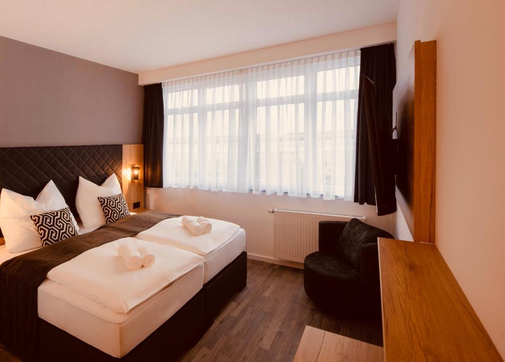 汉诺威MiDoma, Self Check-In Hotel, Hannover Messe的配有一张床和一把椅子的酒店客房