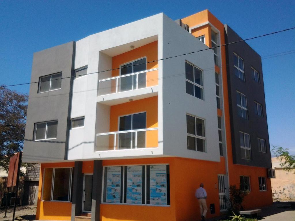 波多诺伏Vannimar Lounge的一座橙色和白色的建筑,前面有一个人站在