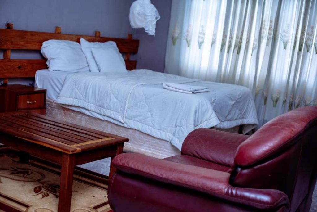ChongweWhite Lotus Lodges Katete的一间卧室配有一张床、一把椅子和一张沙发