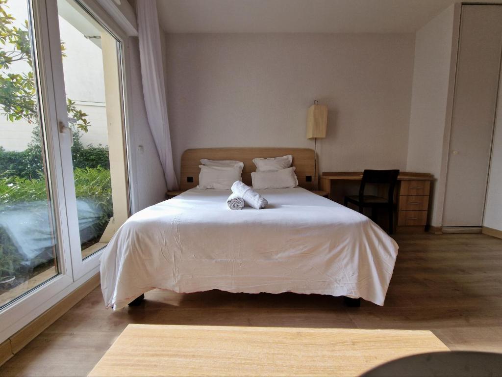迪沃讷莱班Appartement confortable - Proche du lac的一间卧室配有一张带白色床单的床和一扇窗户。