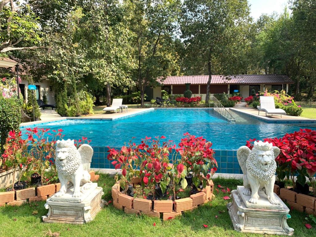 山甘烹Baan Pingkan Wellness Resort的一座拥有两座狮子和花卉雕像的游泳池