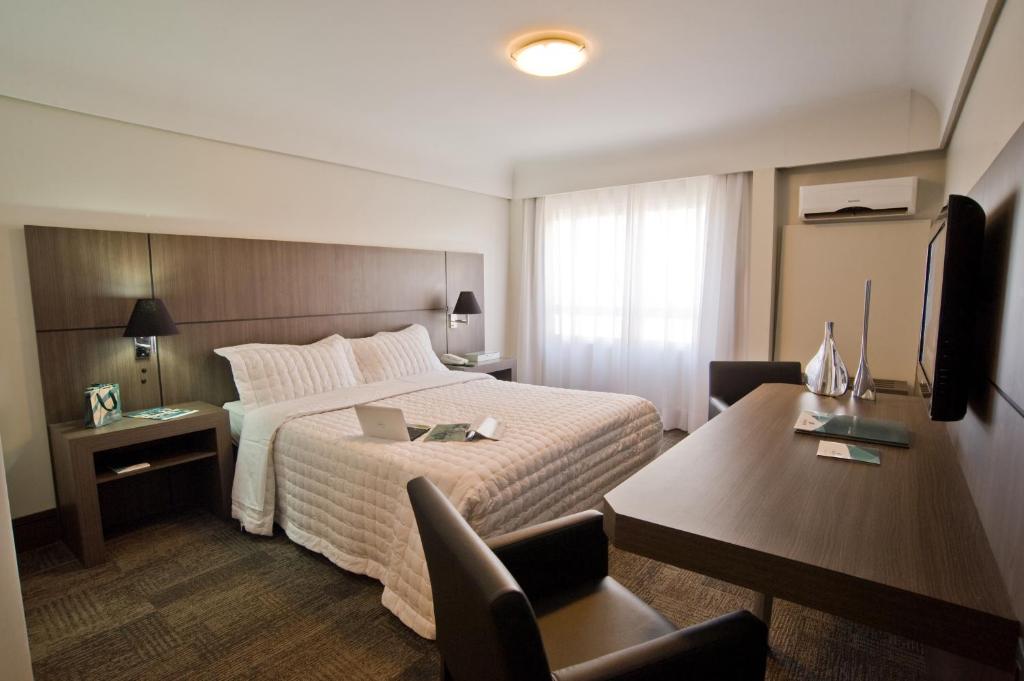 库里提巴Slaviero Curitiba Centro的酒店客房设有一张大床和一张书桌。