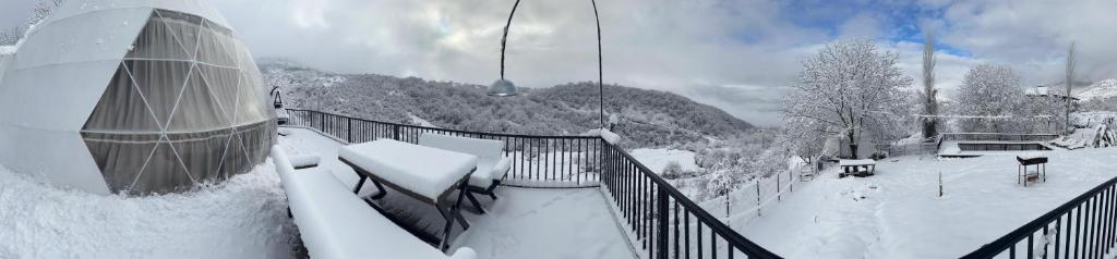 盖贝莱Dream Domes Glamping的雪覆盖的滑雪小屋阳台,上面有雪