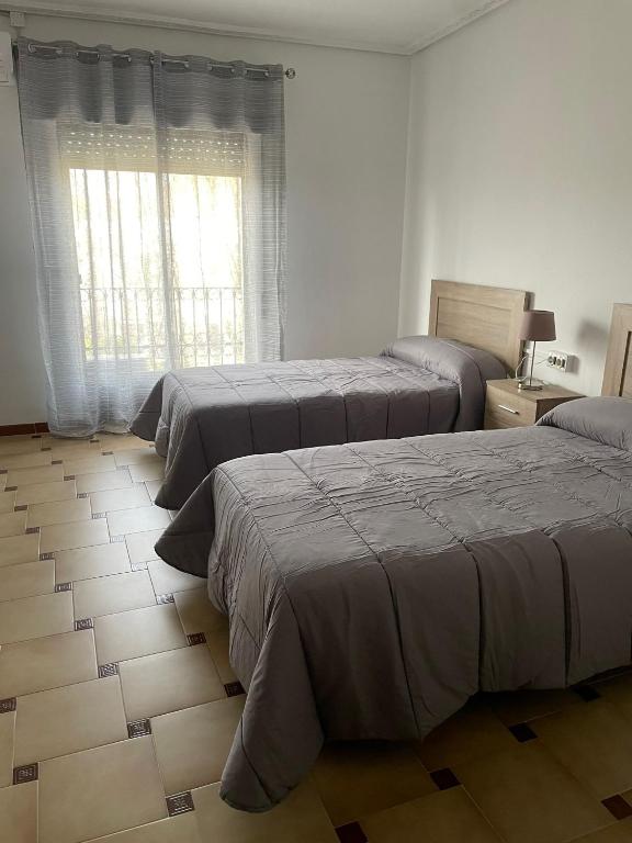 巴埃萨APARTAMENTOS LEONOR的一间卧室设有三张床和窗户。