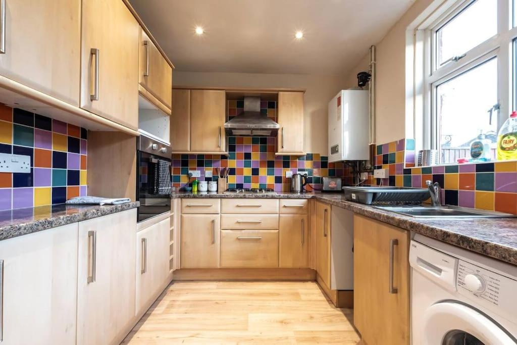 南安普敦Bluebell House的厨房配有木制橱柜,墙上铺有色彩缤纷的瓷砖。