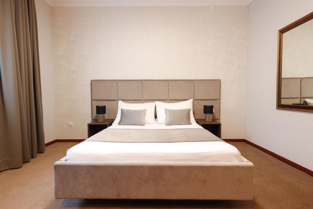 巴尼亚卢卡维多维奇酒店的一间卧室配有一张带两盏灯的大型白色床。