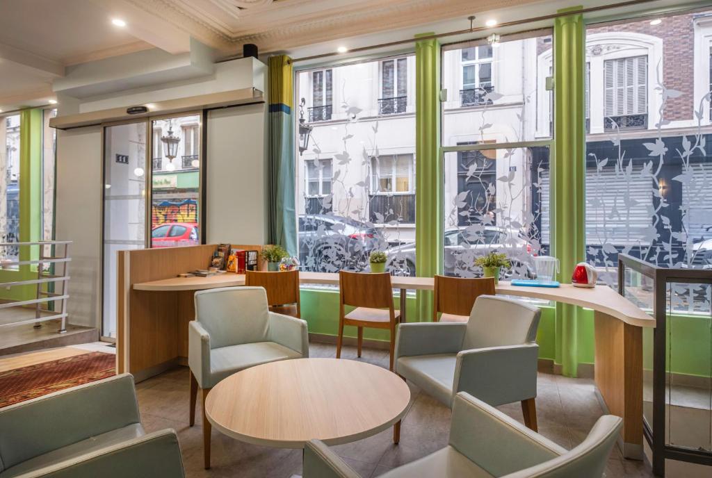 巴黎圣乔治拉法耶特酒店的餐厅设有桌椅和大窗户。