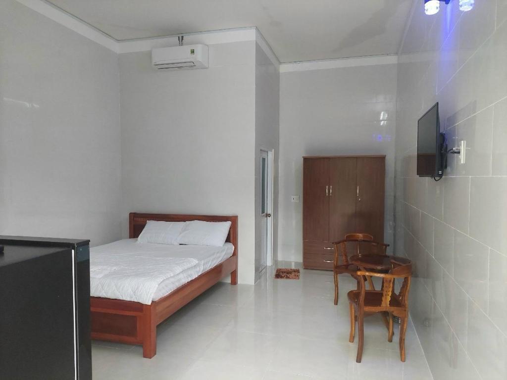 富国Nhà Nghỉ Tốt Hơn的卧室配有1张床、1张桌子和1把椅子
