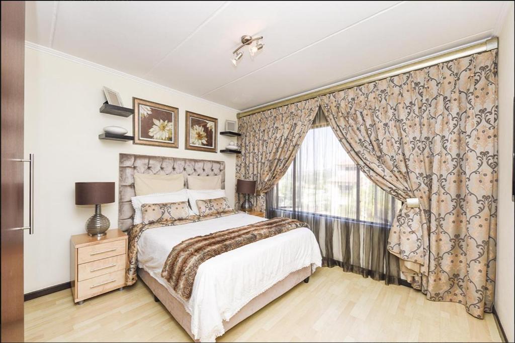 SandtonThe Kanyin的一间卧室配有床和带窗帘的窗户