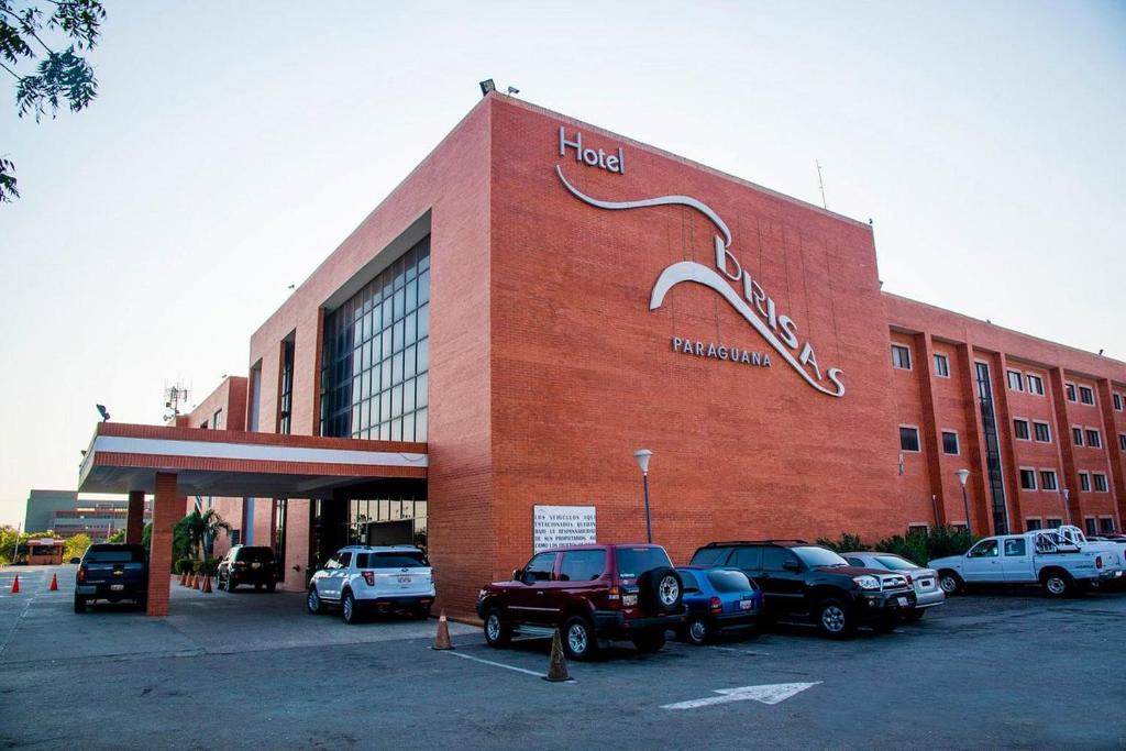 Punto FijoHOTEL BRISAS PARAGUANÁ的一座大型红砖建筑,停车场内有车辆停放