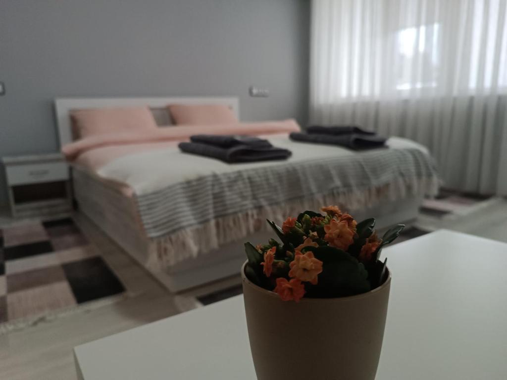 戈采代尔切夫City Apartment的一间卧室配有一张床,一个花瓶摆放在桌子上