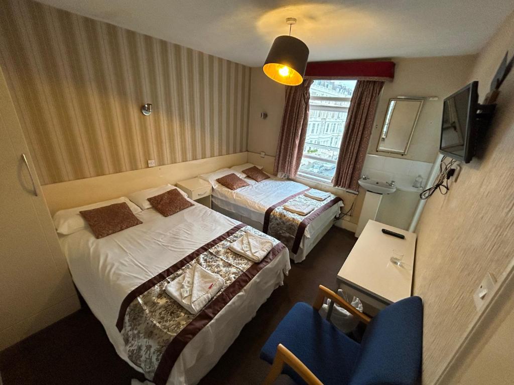 伦敦伯爵府酒店的酒店客房,配有两张床和椅子