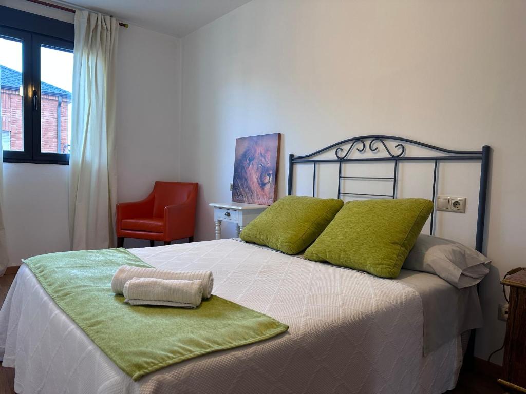 蓬费拉达Suite Rigel的一间卧室配有一张带绿色枕头的床和一张红色椅子