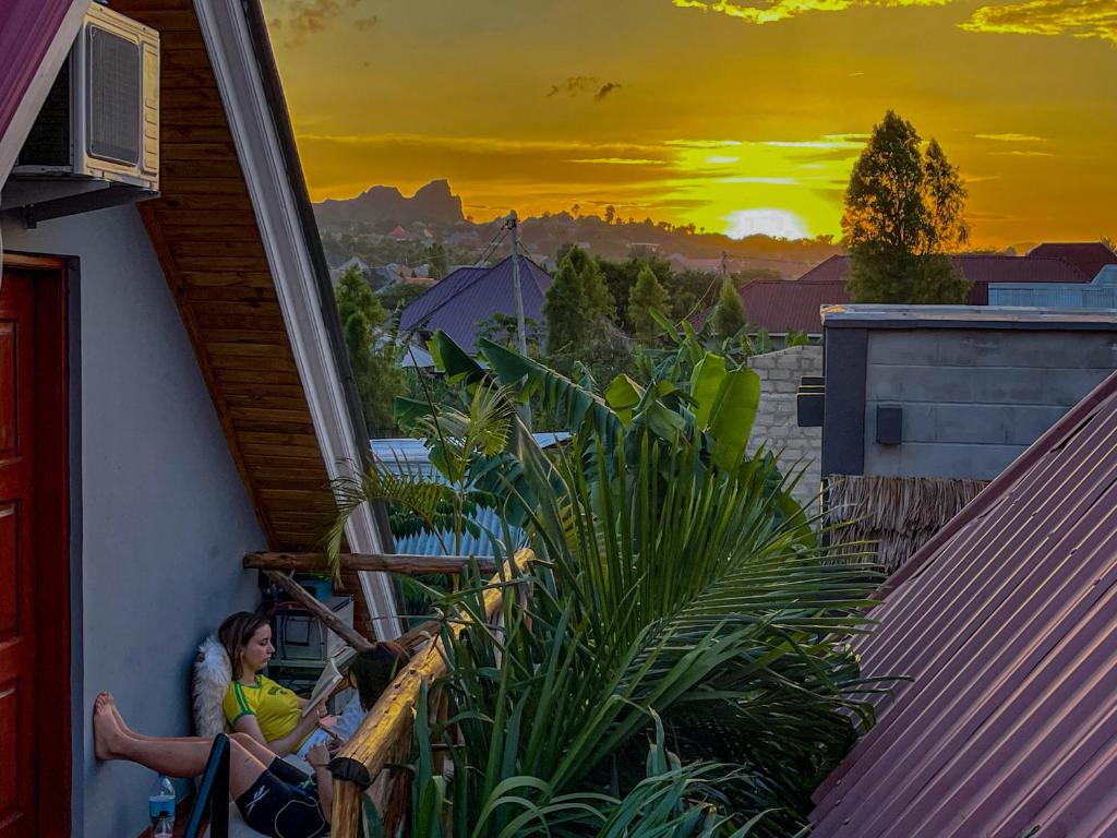 阿鲁沙Home Villa Arusha的坐在房子阳台上的女人,欣赏日落