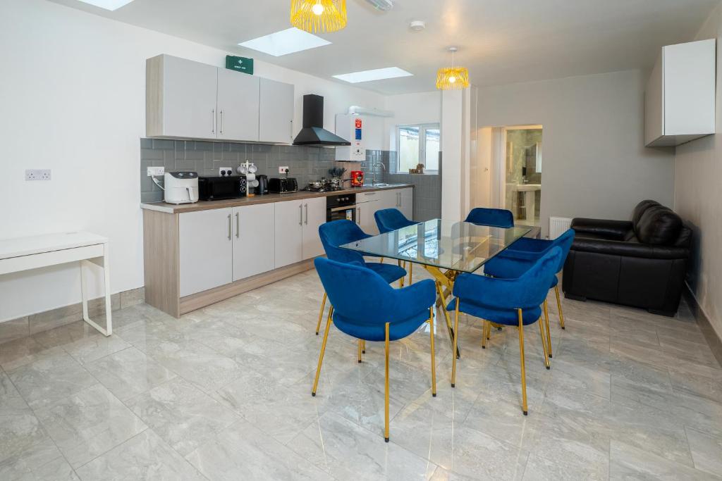 伯明翰Kunda House Coventry Road的厨房以及带玻璃桌和蓝色椅子的用餐室。