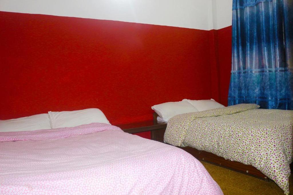 DeorāliYours Family Restaurant and Homestay的一间卧室设有两张床和红色的墙壁