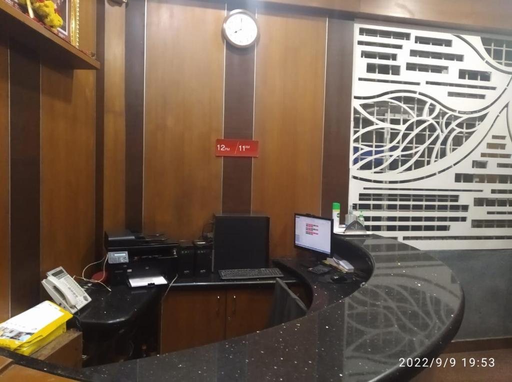 班加罗尔The Trinitywood Hotel & Restaurant的办公室配有带笔记本电脑和电话的书桌