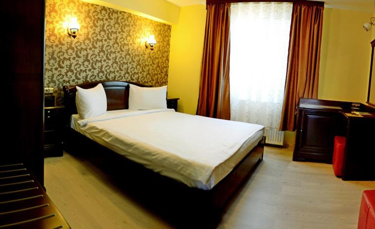 克卢日-纳波卡Pensiunea Junior的卧室配有一张带白色床单的大床和窗户。
